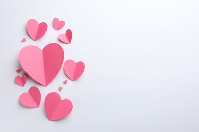 Photo of Pink paper hearts on white background, flat lay. Space for text