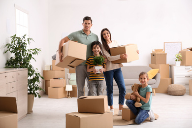 Happy family in room with cardboard boxes on moving day