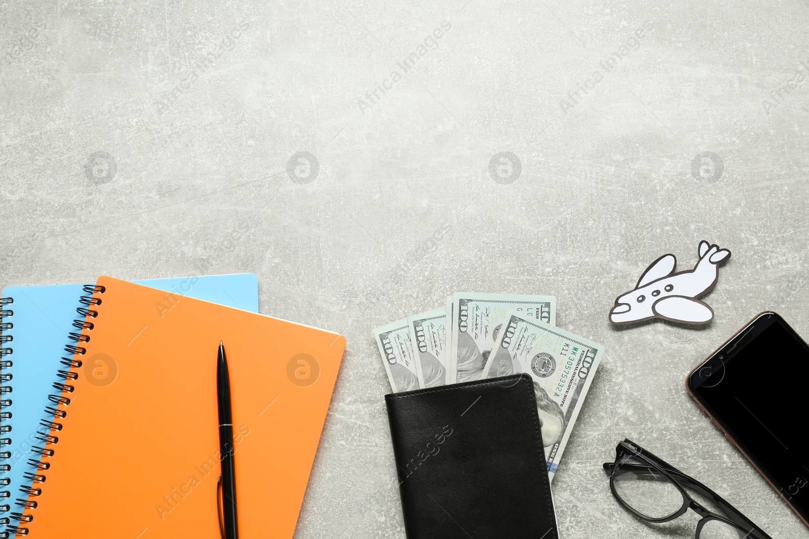 Photo of Flat lay composition with dollars, notebooks and passport on light grey table, space for text. Business trip