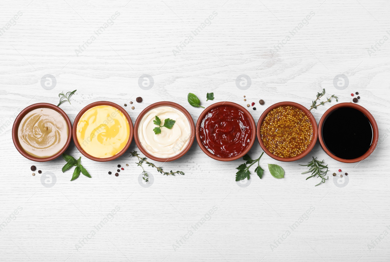 Photo of Many different sauces and herbs on white wooden table, flat lay