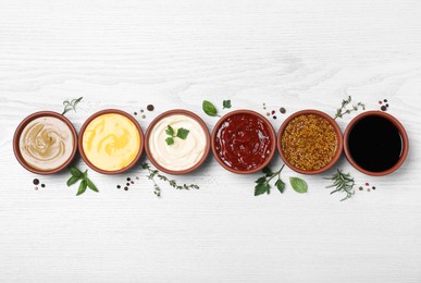 Photo of Many different sauces and herbs on white wooden table, flat lay