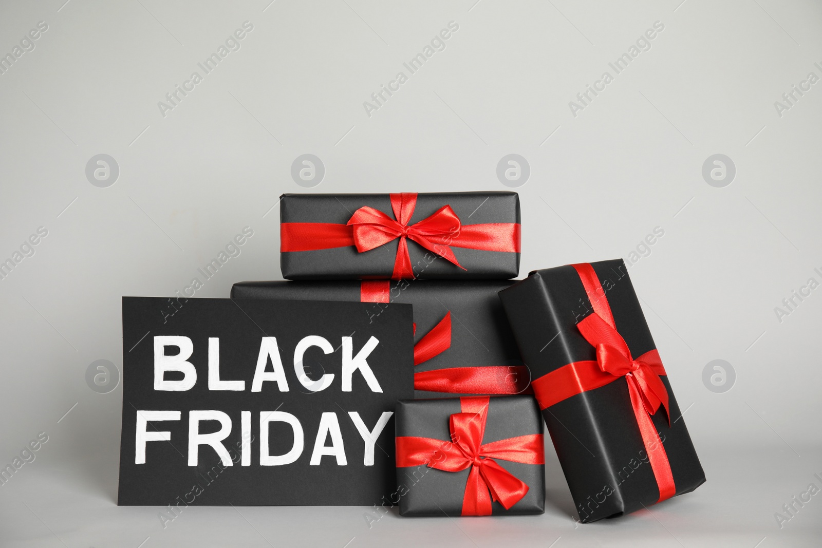 Photo of Many gift boxes and sheet of paper with words Black Friday on light grey background