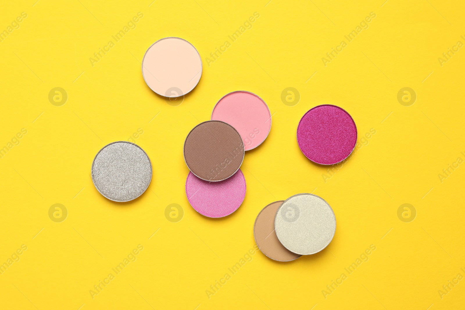 Photo of Beautiful eye shadow refill pans on yellow background, flat lay