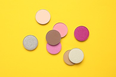 Beautiful eye shadow refill pans on yellow background, flat lay