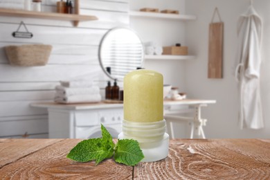 Natural crystal alum deodorant and mint leaves on wooden table in bathroom