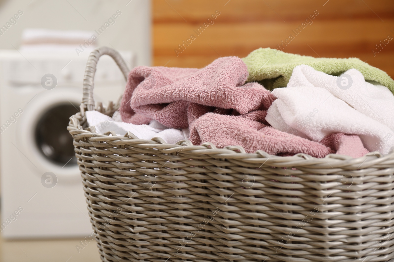 Photo of Wicker basket with dirty laundry in bathroom, closeup