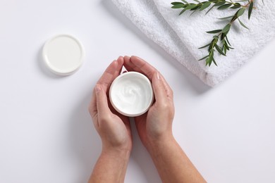 Photo of Woman with jar of hand cream, towel and green twigs on white background, top view