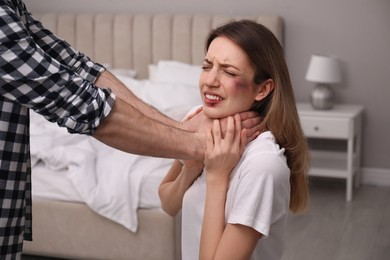 Photo of Man abusing scared woman in bedroom. Domestic violence