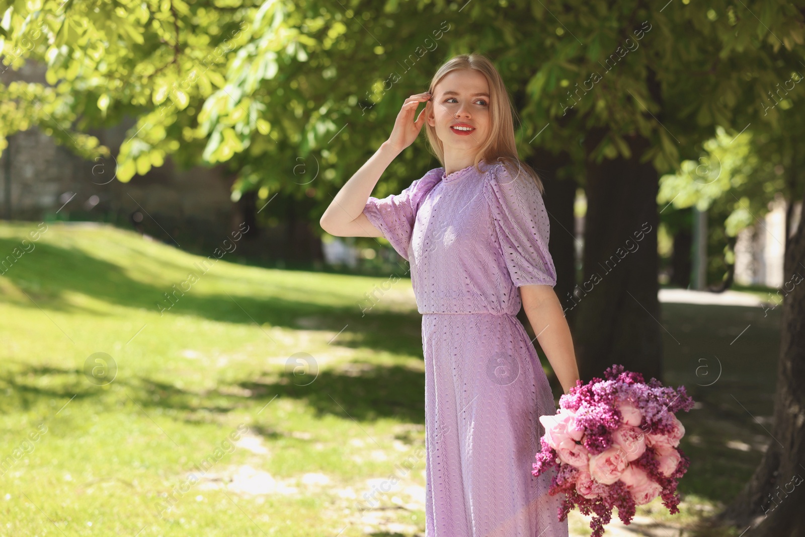 Photo of Beautiful woman with bouquet of spring flowers in park on sunny day, space for text