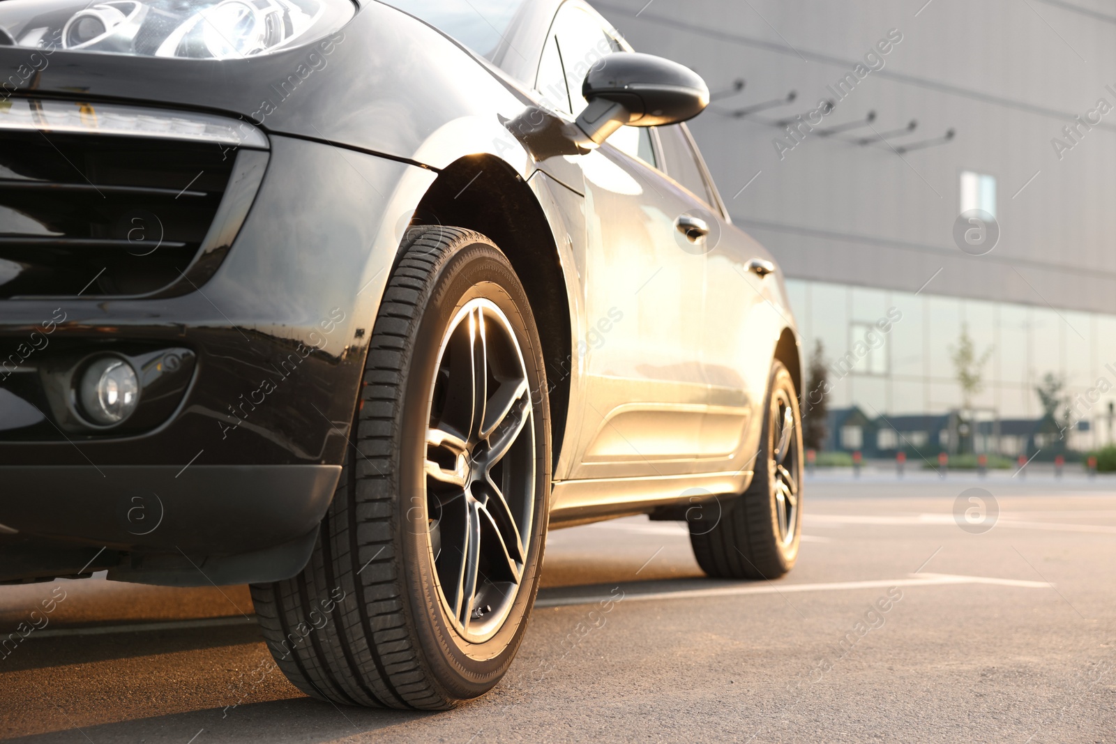 Photo of Modern black car parked on asphalt road outdoors