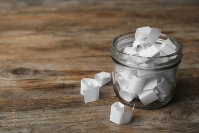 Photo of Glass jar with paper pieces on wooden table, space for text