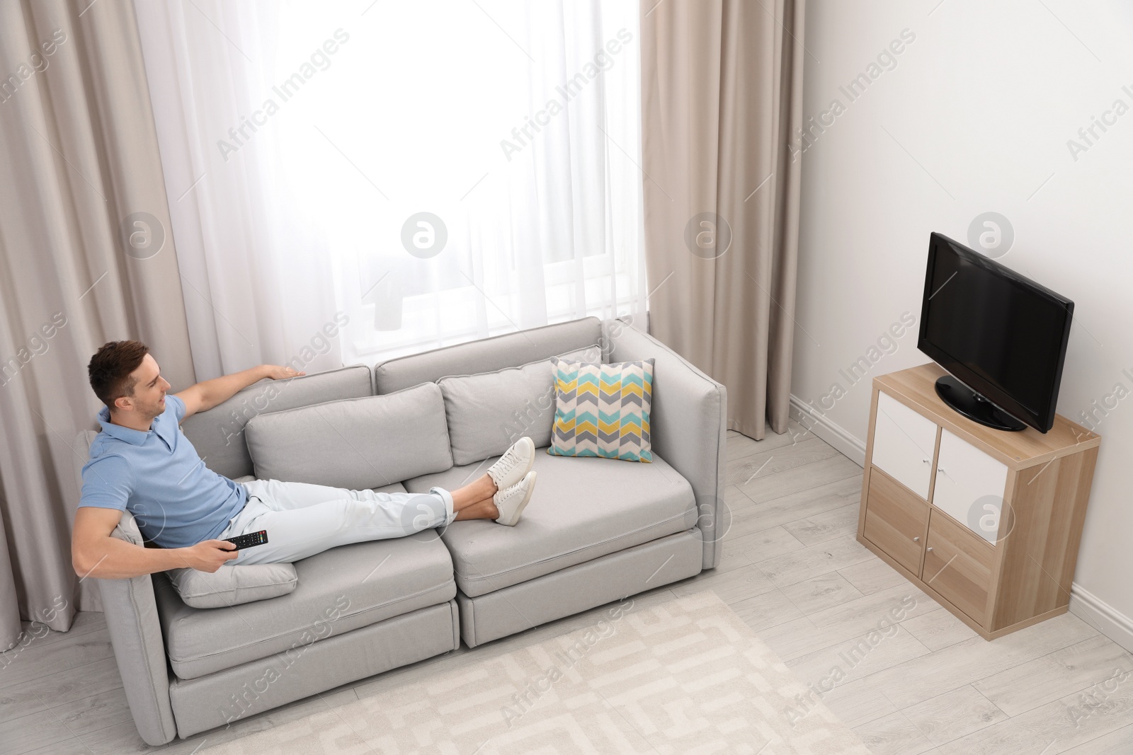 Photo of Man watching TV on sofa in living room, view from above. Space for text