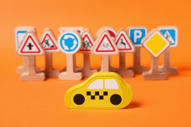 Photo of Set of wooden road signs and car on orange background. Children's toy