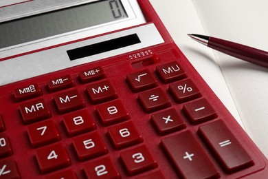 Photo of Calculator and pen on open notebook, closeup