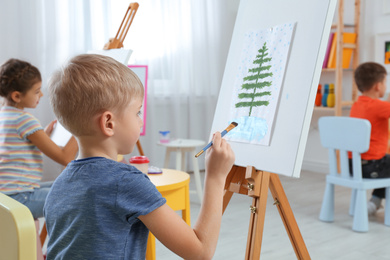 Cute little child painting during lesson in room