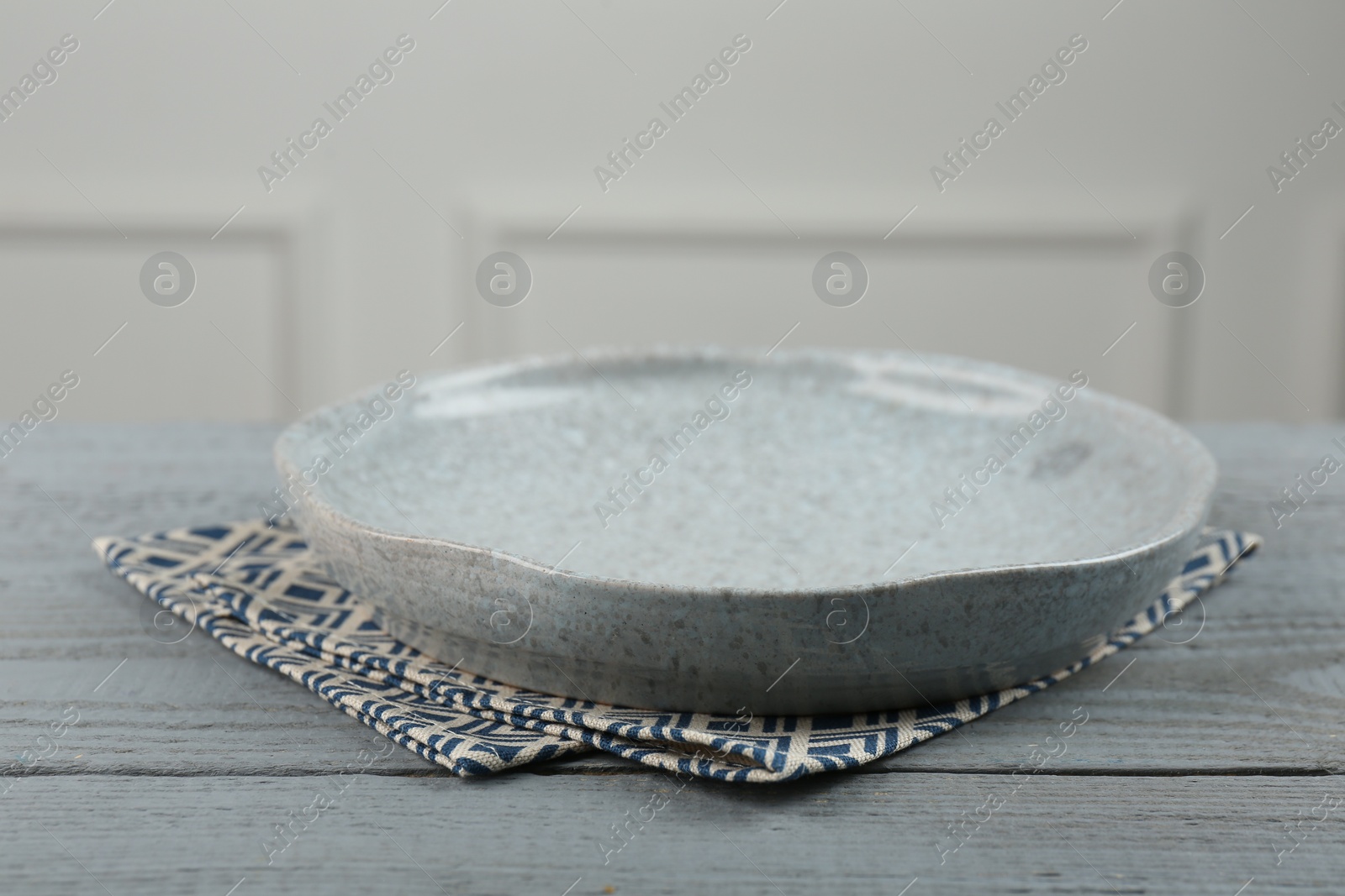 Photo of Beautiful ceramic plate and napkin on gray wooden table indoors, closeup