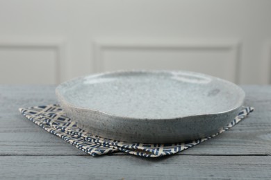 Beautiful ceramic plate and napkin on gray wooden table indoors, closeup