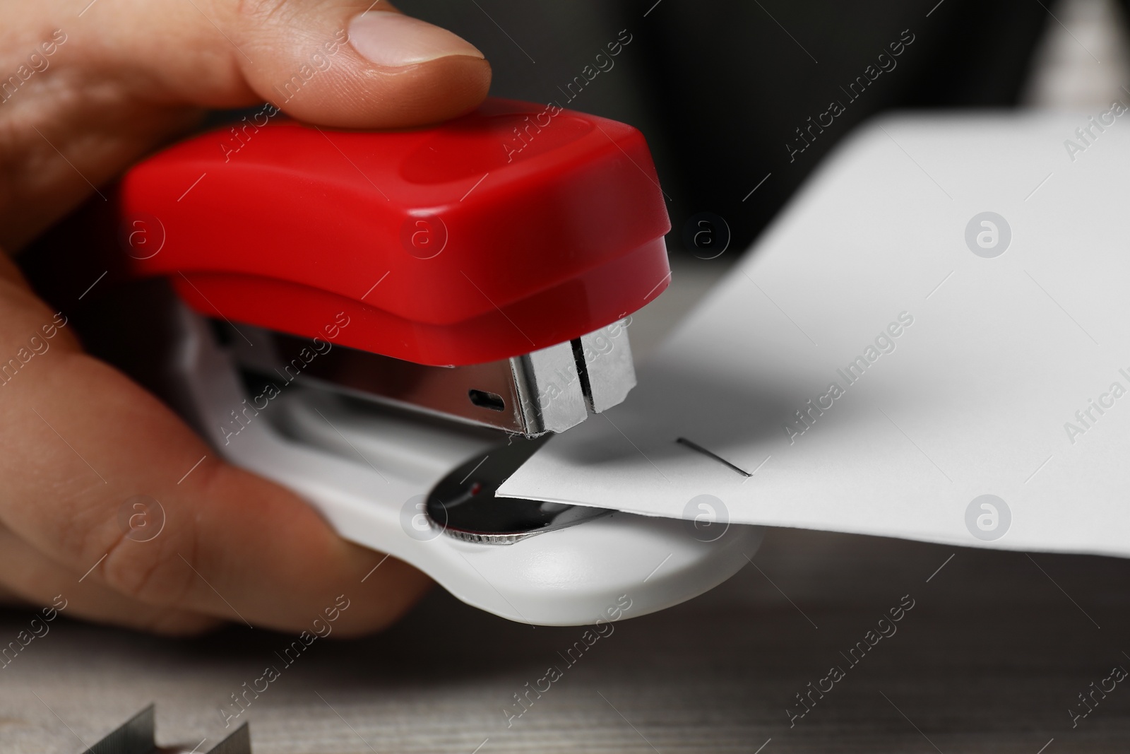 Photo of Woman with papers using stapler at table, closeup