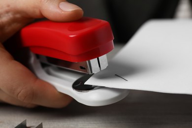 Photo of Woman with papers using stapler at table, closeup