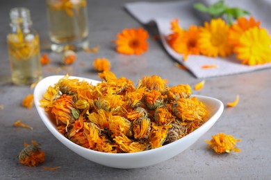 Photo of Plate of dry calendula flowers on light grey table
