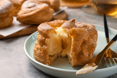 Photo of Delicious profiterole filled with cream on grey table, closeup