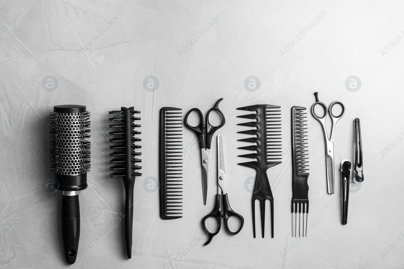 Photo of Flat lay composition with professional hairdresser tools on grey background