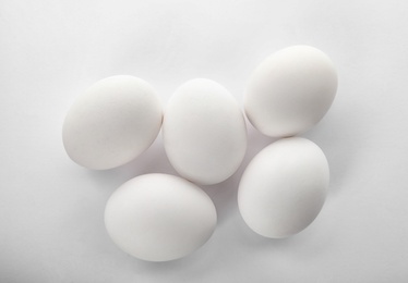 Photo of Raw chicken eggs on white background, top view