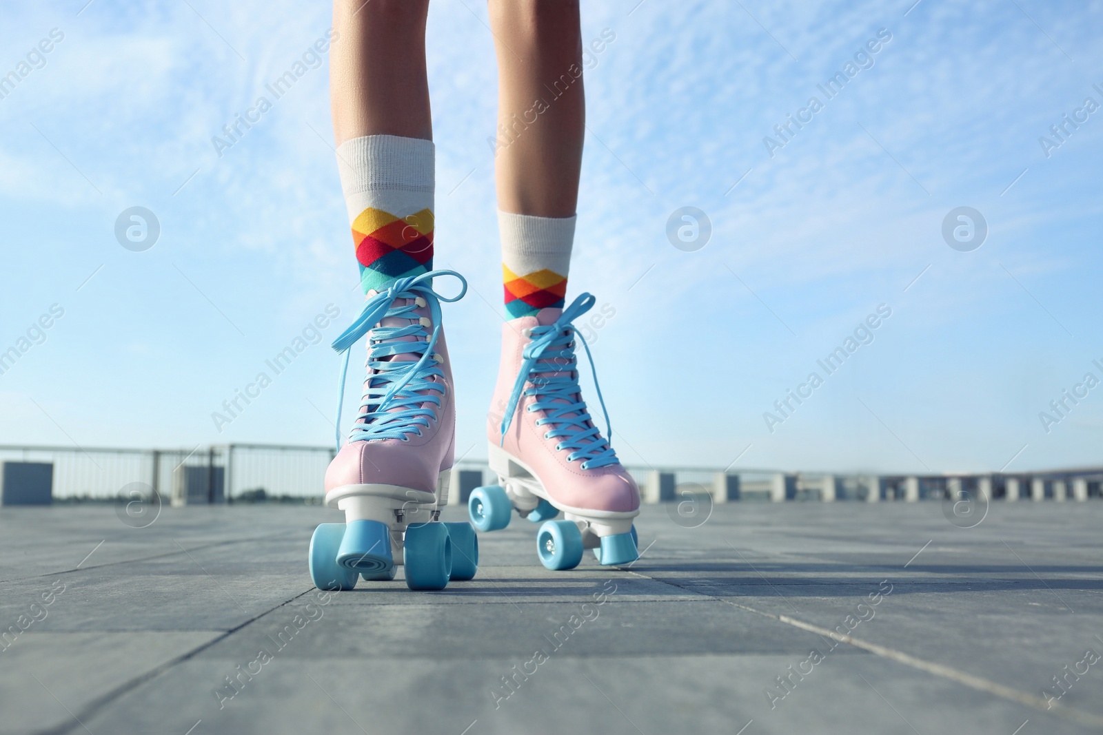 Photo of Young woman with vintage roller skates in city on sunny day, closeup view