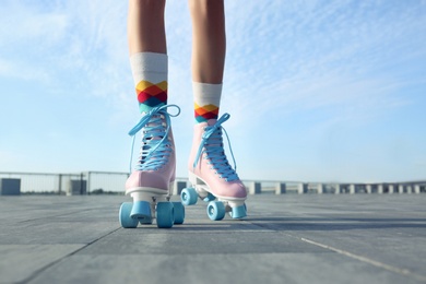 Photo of Young woman with vintage roller skates in city on sunny day, closeup view