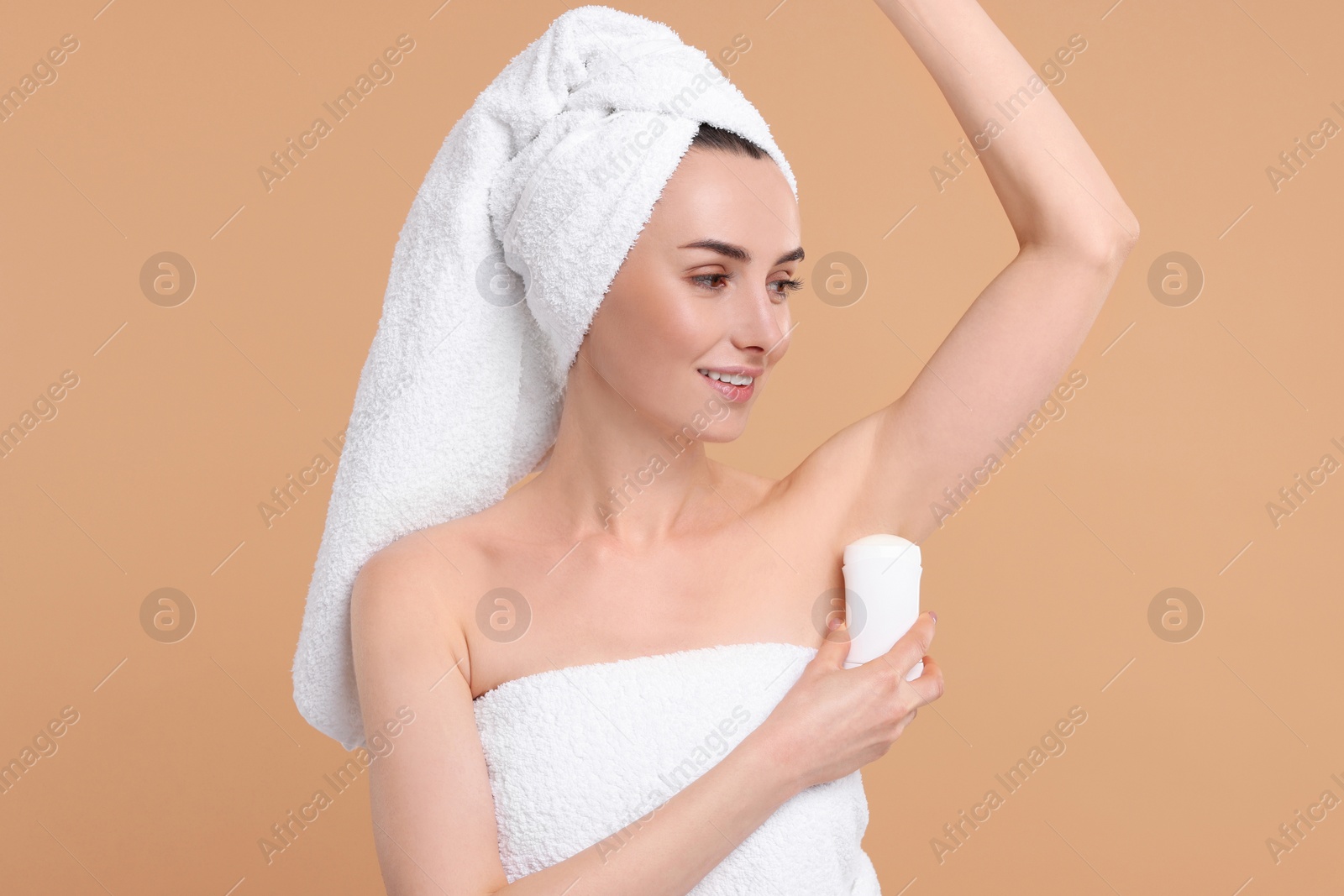 Photo of Beautiful woman applying deodorant on beige background