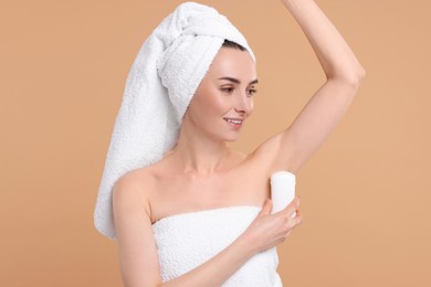 Beautiful woman applying deodorant on beige background