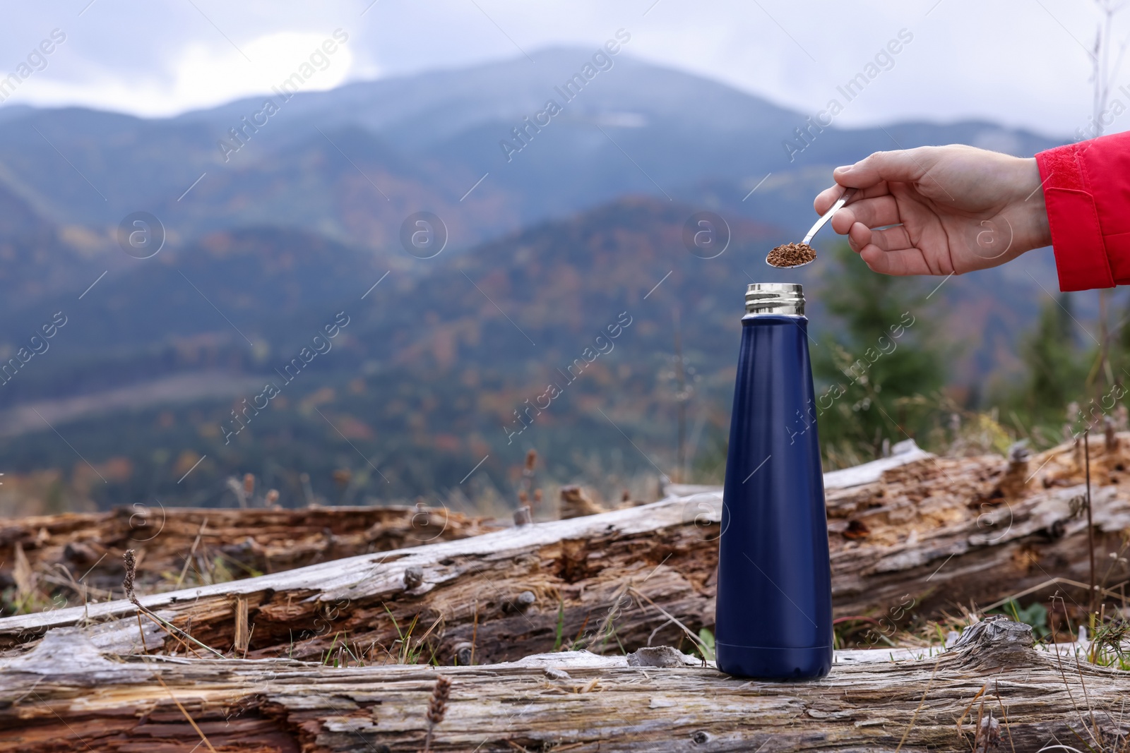 Photo of Woman pouring instant coffee into thermo bottle in mountains, closeup. Space for text