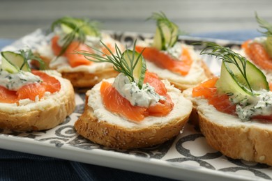 Photo of Tasty canapes with salmon, cucumber, cream cheese and dill on table, closeup