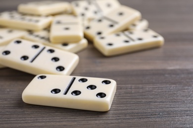 Photo of Domino tiles on wooden table, closeup. Space for text