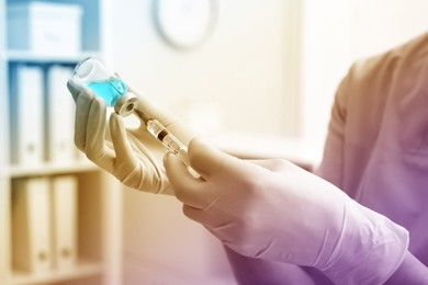 Doctor filling syringe with medication from vial in hospital, closeup