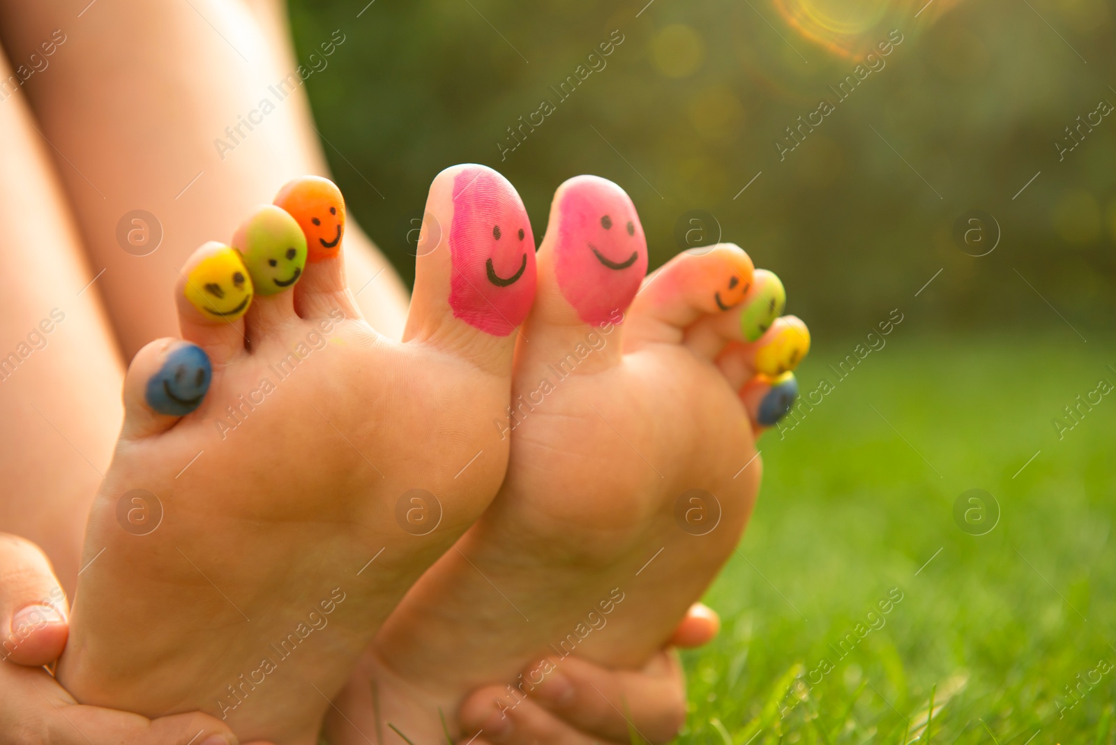 Photo of Teenage girl with smiling faces drawn on toes outdoors, closeup