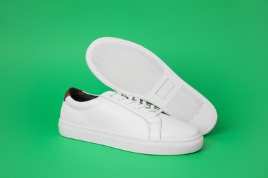 Photo of Pair of stylish white sneakers on green background
