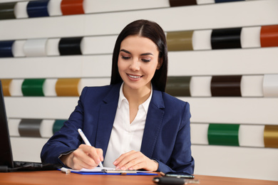 Saleswoman working at desk in car dealership