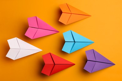 Photo of Handmade colorful paper planes on yellow background, flat lay