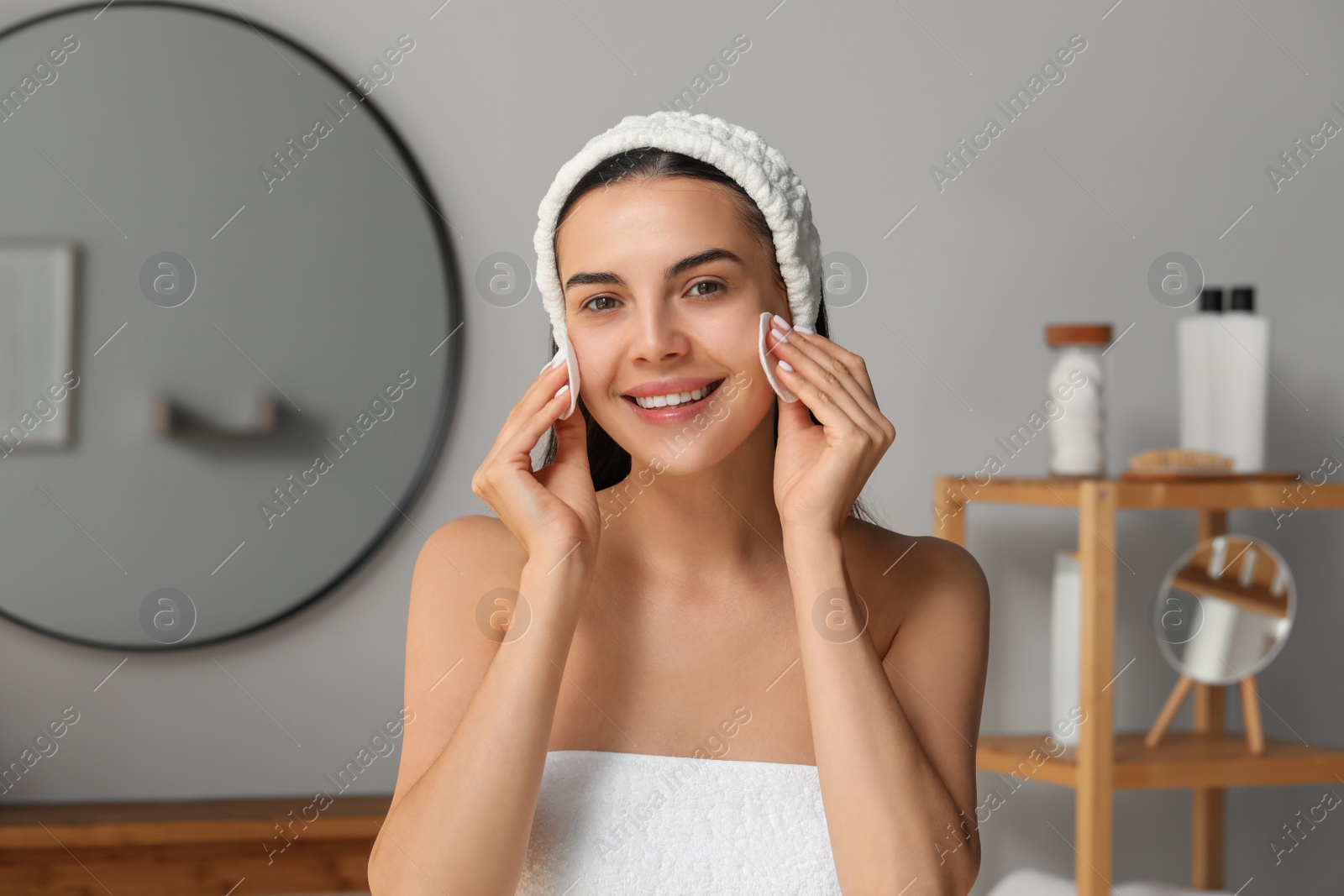 Photo of Young woman using cotton pads with micellar water indoors