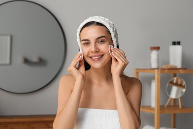 Young woman using cotton pads with micellar water indoors