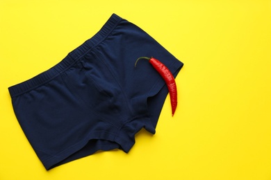 Men's underwear and chili pepper on yellow background, flat lay. Potency problem concept