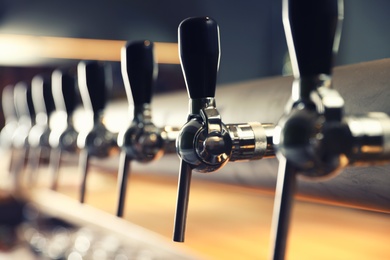 Row of shiny beer taps in pub, closeup