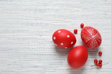 Photo of Flat lay composition with painted Easter eggs on wooden table, space for text