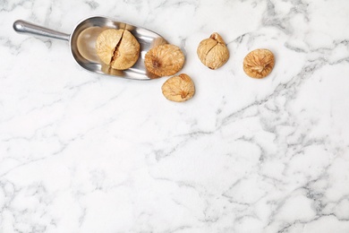 Photo of Scoop of dried figs on marble table, top view with space for text. Healthy fruit