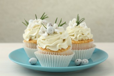 Tasty Easter cupcakes with vanilla cream on light wooden table, closeup