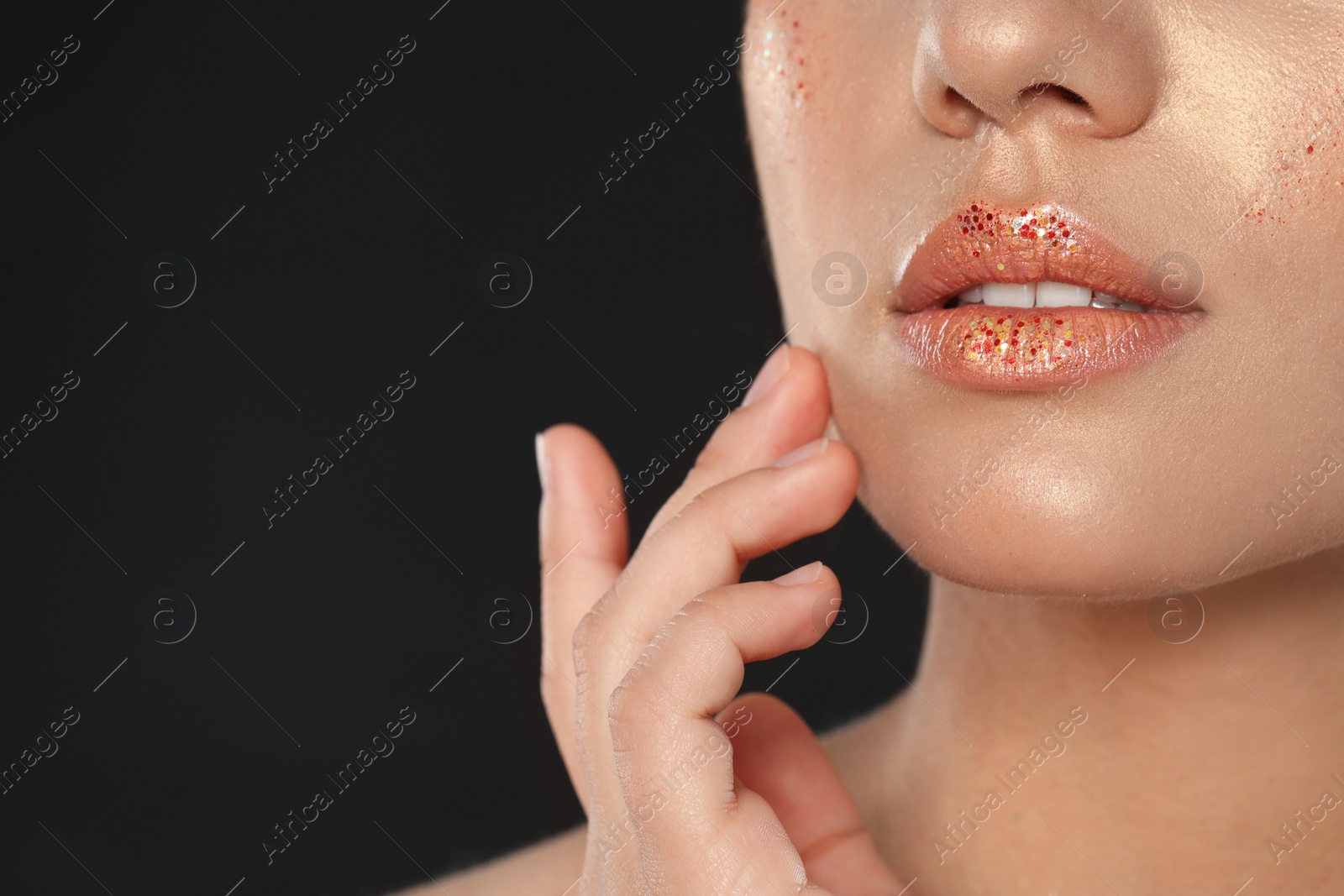 Photo of Beautiful young woman with glitter makeup on black background, closeup view. Space for text