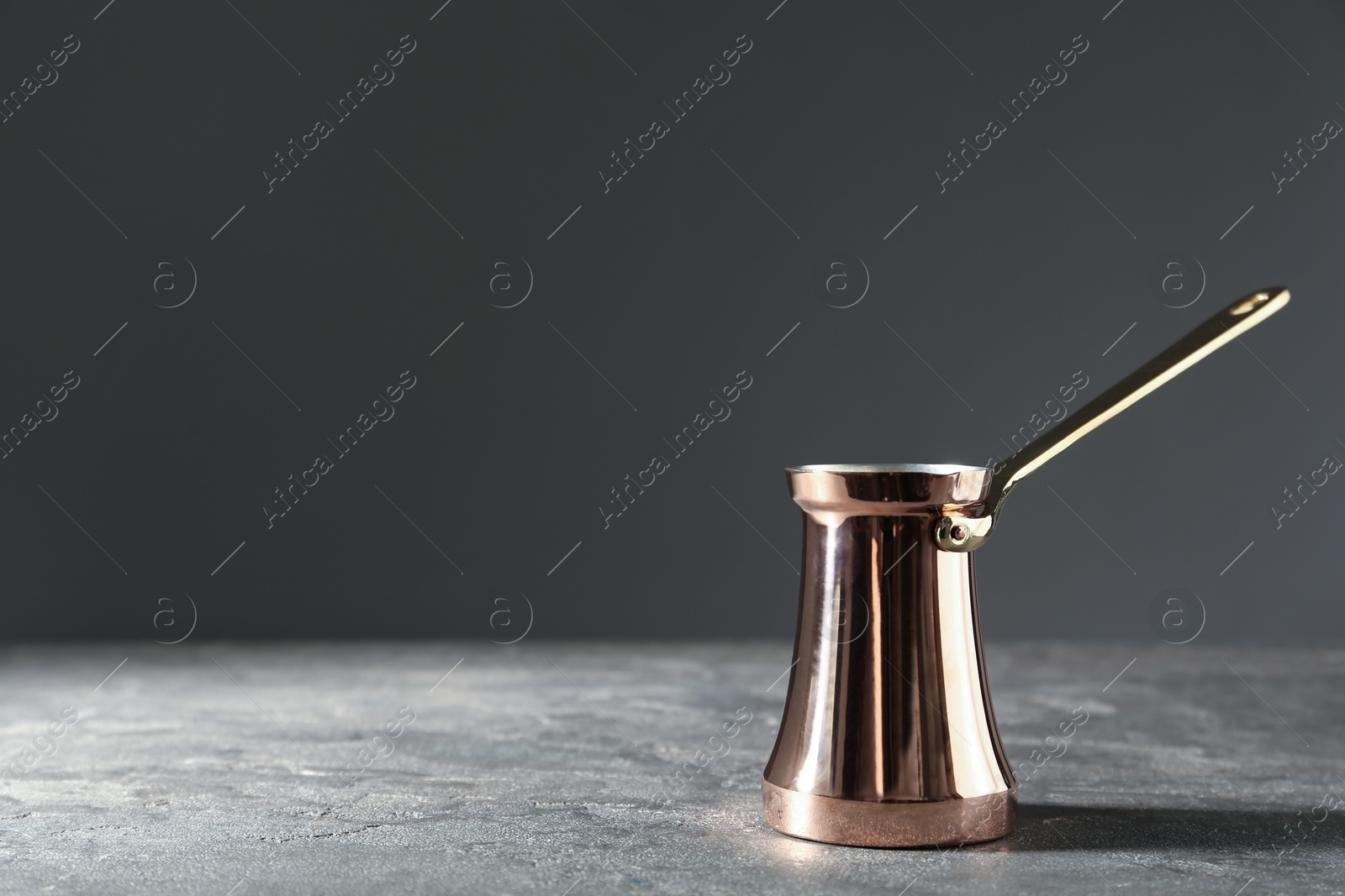 Photo of Beautiful copper turkish coffee pot on grey table. Space for text