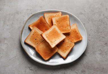 Plate with slices of delicious toasted bread on gray table, top view