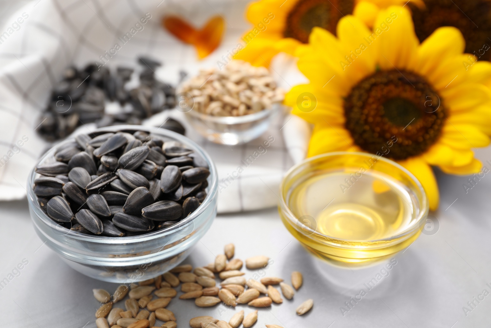 Photo of Sunflower oil and seeds on grey table, closeup